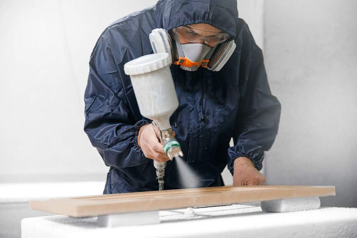 Person spray paining with a spray gun
