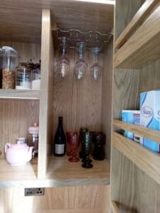 Kitchen larder unit with wine glass holders and integrated electrical points