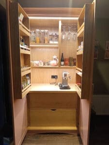 Kitchen larder units with wine, wine glasses and coffee maker. The doors have wooden spice racks