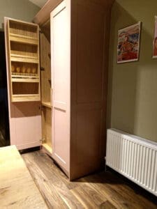 Oak spice rack on pink kitchen larder unit