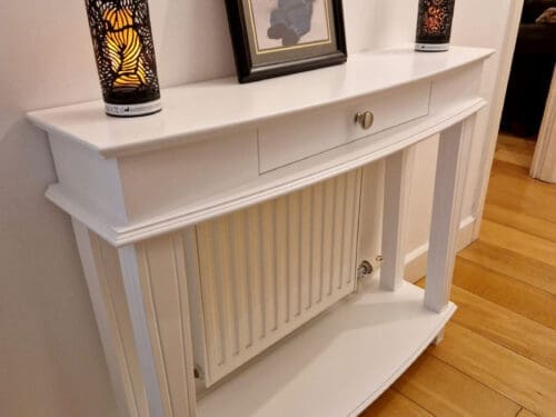 console table with curved top and lower shelf covering a radiator.